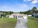 Well-kept single-story home featuring a manicured lawn, mature landscaping, and an attached two-car garage at 2585 Waterfall Dr, Spring Hill, FL 34608