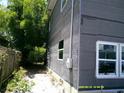 Side exterior of the home shows unfinished covering, new windows, and green foliage at 2914 N 17Th St, Tampa, FL 33605