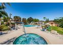 Relaxing community pool area with ample seating, umbrellas, hot tub and lush landscaping with palm trees at 3838 Lanyard Ct # 3838, New Port Richey, FL 34652