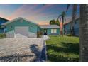 Charming aqua home with a paver driveway, complemented by lush green lawn and landscaping at 4482 Kingston Dr, Hernando Beach, FL 34607