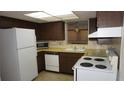 Functional kitchen featuring laminate countertops, white appliances and dark wooden cabinetry with ample storage at 5636 Dolores Dr, Holiday, FL 34690