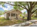 A cozy bungalow home boasts a classic design, enhanced by a spacious front porch and mature tree at 6207 Main St, New Port Richey, FL 34653
