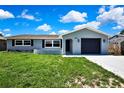 Inviting single-story home showcasing a gray exterior and a well-manicured green lawn at 6306 Aberdeen Ave, New Port Richey, FL 34653