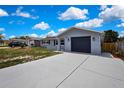 Gray single-story home with a dark-colored garage door and concrete driveway, set against a blue sky with white clouds at 6306 Aberdeen Ave, New Port Richey, FL 34653