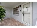 Close-up of the front entry featuring brick flooring and a white storm door at 7735 Farmlawn Dr, Port Richey, FL 34668