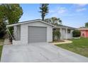 View of the home's exterior with a gray garage door, gray rock facade and concrete driveway at 7735 Farmlawn Dr, Port Richey, FL 34668