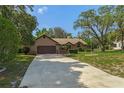 Spacious driveway leading to a well-maintained home with mature trees and a tidy front yard at 8402 Lake Hill Ct, Spring Hill, FL 34608