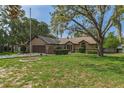 Inviting single-story home featuring a large, well-maintained front lawn and mature trees for shade at 8402 Lake Hill Ct, Spring Hill, FL 34608