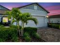 Close up of a single car garage on a charming home with manicured landscaping including small palm trees along the driveway at 8431 Ocean Tides Cv, Parrish, FL 34219