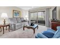 Comfortable living room featuring a gray sofa, a glass top coffee table and sliding glass door to the lanai at 9334 Whitstone Ct, New Port Richey, FL 34655