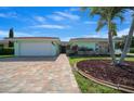 Charming home with a well-manicured lawn, brick driveway, and mature palm trees at 9810 San Sebastian Way, Port Richey, FL 34668