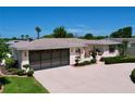 Low angle shows a single-story home's two-car garage, garden boxes and manicured shrubs at 10111 Glen Moor Ln, Port Richey, FL 34668