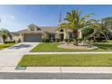 Delightful one-story home featuring a lush lawn, a decorative palm tree, and a practical two-car garage at 1049 Larkin Rd, Spring Hill, FL 34608