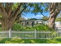 Charming single story home with a white picket fence, mature trees and lush front yard landscaping at 1115 Pennsylvania Ave, Palm Harbor, FL 34683