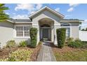Inviting front entrance with a brick pathway, manicured bushes, and an arched entryway leading to the front door at 11192 Archer Ave, Spring Hill, FL 34608