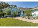 Inviting front entrance with a brick walkway, lush landscaping, and a charming light blue exterior at 3609 Montclair Dr, New Port Richey, FL 34655