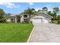 Inviting single-story home with a long driveway, two-car garage, lush green lawn, and mature landscaping at 487 Waterloo Ct, Spring Hill, FL 34609