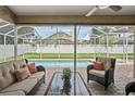 A covered outdoor living space featuring comfortable wicker furniture with views of the refreshing screened-in pool at 4923 Fort Peck Rd, New Port Richey, FL 34655