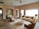 Bright living room with neutral furniture, a ceiling fan, an area rug, and large windows overlooking the backyard at 5701 Brackenwood Dr, Spring Hill, FL 34609