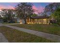A charming home with a well-manicured lawn and beautiful outdoor lighting at twilight at 6315 Shane Ln, New Port Richey, FL 34653