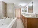 Bathroom featuring a soaking tub, double sink vanity, and neutral ceramic tile at 700 Starkey Rd # 622, Largo, FL 33771