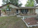 Home featuring a rock facade and a charming front porch with chairs and a small table at 7421 Fairfax Dr, Port Richey, FL 34668