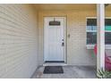 Close-up of the front door with glass window, hardware and potted plant on porch at 7830 Ilex Dr, Port Richey, FL 34668