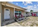 A quaint front porch with seating, a black mulch flower bed, and concrete flooring at 7830 Ilex Dr, Port Richey, FL 34668