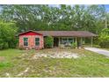 Quaint single-Gathering home with red brick facade, green paint, and a covered carport at 8102 Fort Dade Ave, Brooksville, FL 34601