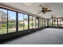 Enclosed lanai featuring floor-to-ceiling windows offering backyard views and ceiling fans at 8700 Wind Mill Dr, New Port Richey, FL 34655