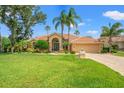 Inviting exterior with lush green lawn, elegant arched entryway, and perfectly manicured landscaping at 9161 Southern Comfort Ct, Weeki Wachee, FL 34613