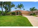 Charming home with meticulously maintained lawn, mature palm trees, and tile roof, creating a welcoming entrance at 9161 Southern Comfort Ct, Weeki Wachee, FL 34613