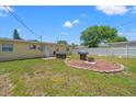 Spacious backyard with lush lawn, grilling area, fire pit, and white privacy fence at 9891 52Nd N St, Pinellas Park, FL 33782