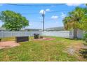 Large backyard with a grilling area, fire pit, storage box, and white privacy fence at 9891 52Nd N St, Pinellas Park, FL 33782