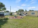 Expansive backyard with green grass, patio area, grill, fire pit, and white fence at 9891 52Nd N St, Pinellas Park, FL 33782