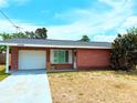 Charming single-story red brick home featuring an attached garage and a well-maintained lawn at 11034 Harding Dr, Port Richey, FL 34668