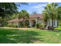 Inviting home with mature landscaping, featuring palm trees and a manicured lawn at 12403 Moneta Rd, Weeki Wachee, FL 34614