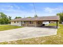 Exterior view of a cozy single story home with a covered parking area and a well maintained lawn at 12936 Parkwood St, Hudson, FL 34669