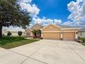 Beautiful tan single-story home with a three-car garage on a well-maintained lawn under a sunny sky at 13248 Linzia Ln, Spring Hill, FL 34609