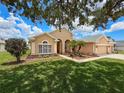 Charming single-story home featuring a well-kept lawn, complemented by mature trees and a welcoming walkway at 13248 Linzia Ln, Spring Hill, FL 34609