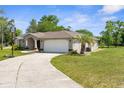 A bright home showing a driveway, landscaping, and attached two car garage at 14031 Hexam Rd, Brooksville, FL 34613