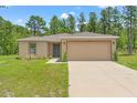 Inviting single-story home with a well-kept lawn, two-car garage, and lush greenery in the landscape at 15414 Green Jay Rd, Weeki Wachee, FL 34614