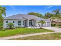 Charming single-story home with manicured lawn, palm trees, and a three-car garage at 18902 Saint Laurent Dr, Lutz, FL 33558
