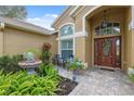 Inviting front porch features tiled flooring, beautiful plants, and an elegant entry door that creates a welcoming entrance at 19418 Morden Blush Dr, Lutz, FL 33558