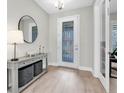 Inviting entryway with decorative door, stylish console table, round mirror, and wood-look flooring at 4056 Burdick Loop, Odessa, FL 33556