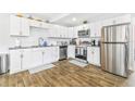Modern kitchen features white cabinets, stainless steel appliances, and wood-look flooring at 4057 67Th N Ave, Pinellas Park, FL 33781