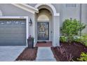 Close-up of front door with brick paver entry, flower arrangement, and attached two-car garage at 4094 Braemere Dr, Spring Hill, FL 34609
