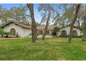 Beautiful home with mature trees, a well-kept lawn, and unique architectural details at 4595 Lake In The Woods Dr, Spring Hill, FL 34607
