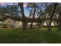 Attractive home exterior with a well-kept lawn and mature trees illuminated by outdoor lights at twilight at 4595 Lake In The Woods Dr, Spring Hill, FL 34607
