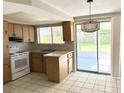 Bright kitchen area with white appliances, wood cabinets and a sliding patio door at 6406 Stone Rd, Port Richey, FL 34668